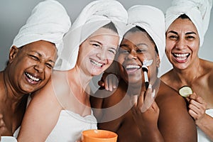 Multigenerational women having fun applying face beauty masks on their face - Main focus on caucasian woman face