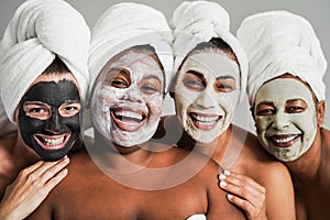 Multigenerational women having fun wearing face beauty mask for skin care therapy - Main focus on african girl face