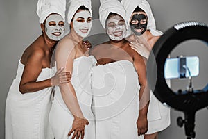 Multigenerational women wwearing face beauty masks while streaming live video with mobile phone