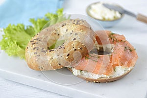Multigrain bagel with cream cheese, salmon slices, dill and salad