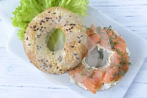 Multigrain bagel with cream cheese, salmon slices, dill and salad, top view