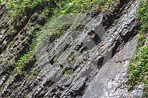 Multilayered dark rocky geological layers on the bank of a mountain river. Rock with visible geological layers_ photo