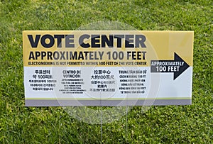 A multilingual voting center sign with arrow and instruction