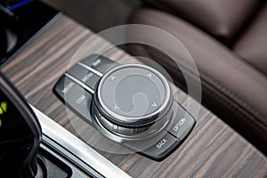 Multimedia system control wheel on a wooden panel in a modern premium luxury exencive new car. close-up, soft focus.