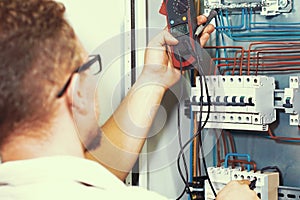 Multimeter is in hands of electrician on background of electrical automation cabinet