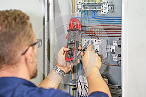 Multimeter is in hands of electrician on background of electrical automation cabinet