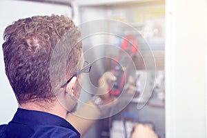 Multimeter is in hands of electrician on background of electrical automation cabinet. An electrician is checking the voltage in