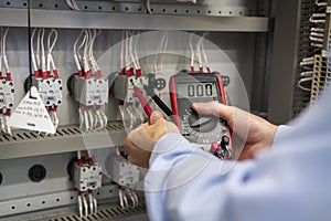 Multimeter in hands of electrician closeup. Service works in electrical box. Maintenance of electric panel