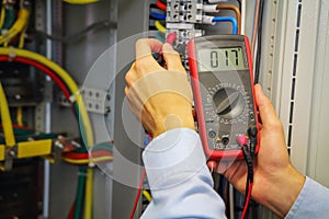 Multimeter in hands of electrician. Engineer adjust electric panel.