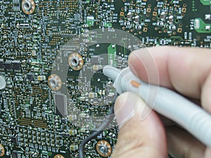 Multimeter probes examining a circuit board