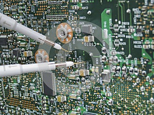 Multimeter probes examining a circuit board