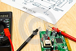 Multimeter probes examining a computer circuit board and circuit