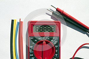 Multimeter with text on display and heat shrink insulation on white background