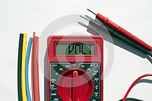 Multimeter with text on display Volt and heat shrink insulation on white background