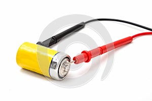 Multimeter wires and yellow battery. Checking battery voltage. Red to plus. Close up, isolated on white background