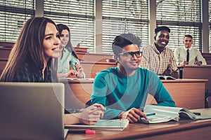 Multinational group of cheerful students taking an active part in a lesson while sitting in a lecture Hall. photo