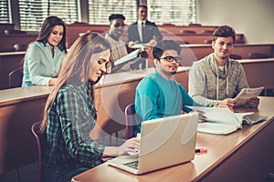 Multinational group of cheerful students taking an active part in a lesson while sitting in a lecture Hall.