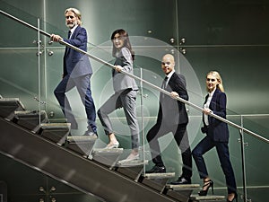 Multiethnic business people walking on steps in modern office