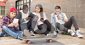 Multinational teenagers play in smartphones in schoolyard