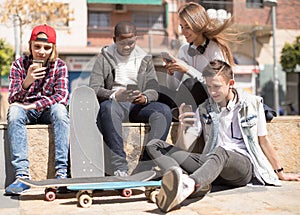 Multinational teenagers play in smartphones in schoolyard