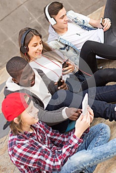 Multinational teenagers play in smartphones in schoolyard