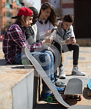 multinational teenagers play in smartphones in schoolyard