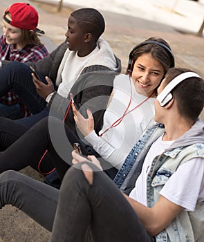 multinational teenagers play in smartphones in schoolyard