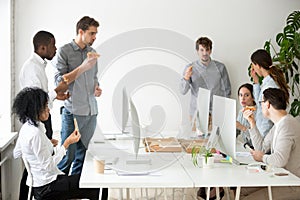 Multinational work group talking and eating pizza at workplace