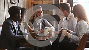 Multinational young friends having fun drinking coffee at coffeehouse table