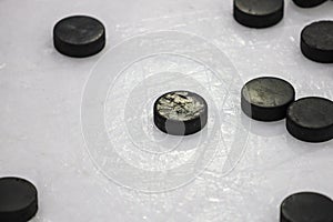 Multiple black Ice Hockey pucks laying on Ice rink ground