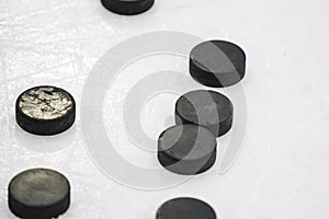 Multiple black Ice Hockey pucks laying on Ice rink ground