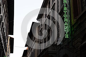 Multiple building facades with an illuminated sign of "RISTORANTE" in green