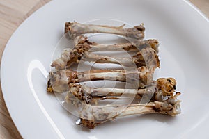 Multiple chicken bones on a white plate