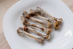 Multiple chicken bones on a white plate
