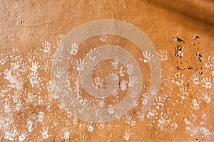 Multiple colorful children hand prints on huskily brown wall