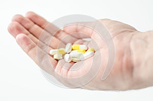 Multiple colors pills in hand on white background, Taking Your Medication.