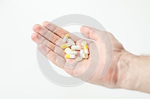 Multiple colors pills in hand on white background, Taking Your Medication.