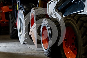 Multiple construction vehicles positioned in storage area featuring robust wheel assemblies