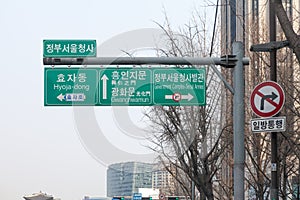 multiple direction sign post with city names in English and Korean