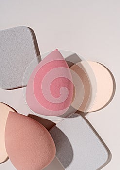 Multiple egg-shaped makeup sponges placed on a beige background