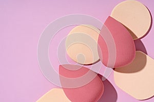 Multiple egg-shaped makeup sponges placed on a pink background