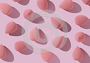 Multiple egg-shaped makeup sponges placed on a pink background