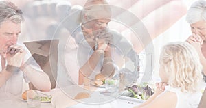 Multiple exposure of caucasain family praying at dinning table and hand with rosary in background