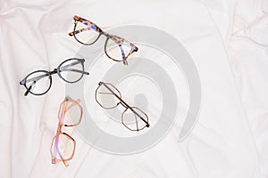 multiple eyes glasses on white crumpled fabric copy space top view