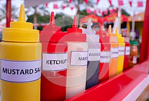 Multiple flavor sauce bottles in a food card at a food festival. Different sauces in plastic