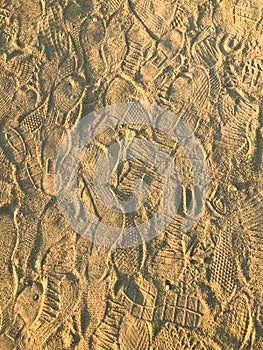 Multiple footprints in the sand desert. Footprints are of shoes, boots and sneakers. A modern but very worn path. Sandy shoe track