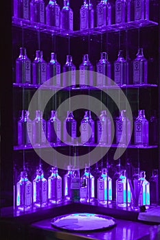 Multiple Gin bottles in purple light decorate shelves in bar in Barcelona, Spain