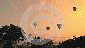 Multiple Hot Air Balloons Floating By at Different Highs on a Golden Early Morning Launch