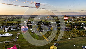 Multiple Hot Air Balloons Soar Over A Picturesque Landscape Featuring A Corn Maze, At Golden Sunset.
