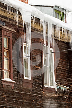 Multiple icicles hang on the edge of the roof, winter or spring.